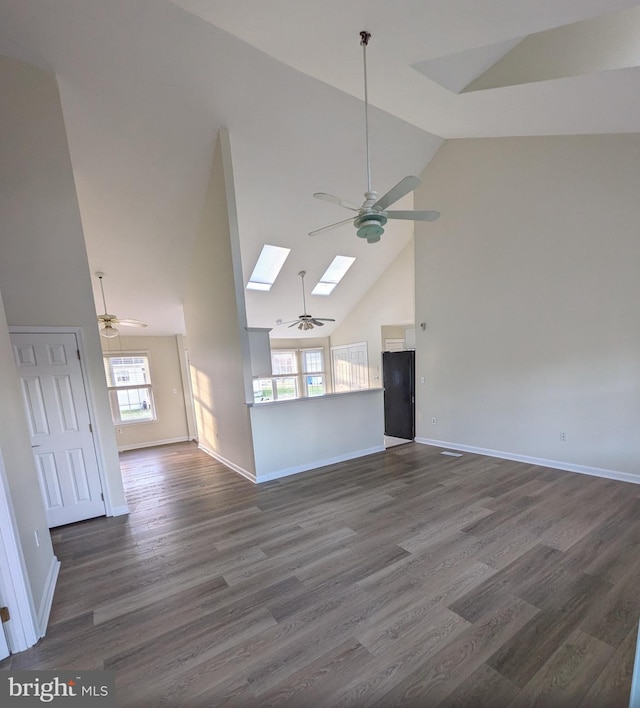 unfurnished living room with a skylight, high vaulted ceiling, and dark wood-type flooring