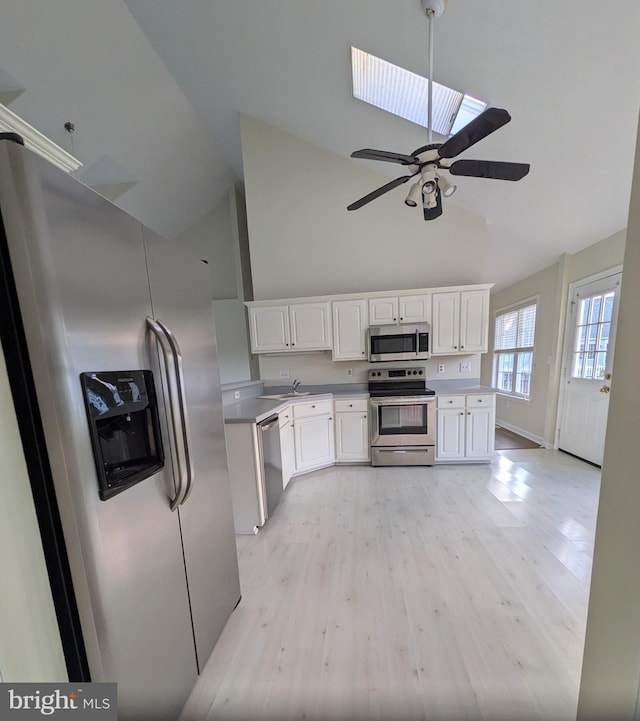 kitchen featuring light wood-type flooring, white cabinetry, appliances with stainless steel finishes, and a skylight