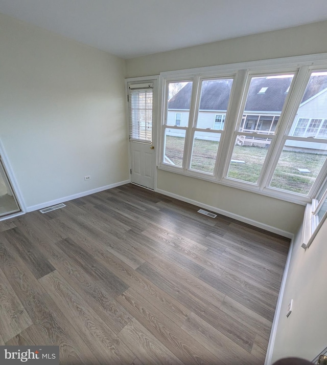 spare room with a wealth of natural light and dark wood-type flooring