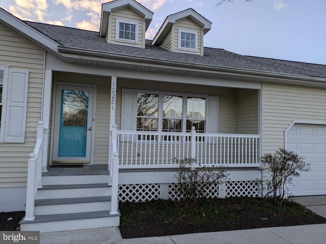 exterior entry at dusk featuring covered porch and a garage