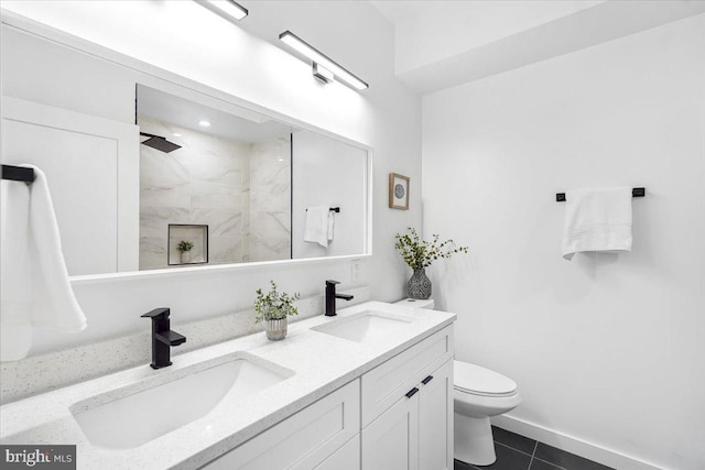 bathroom featuring tiled shower, tile patterned flooring, vanity, and toilet