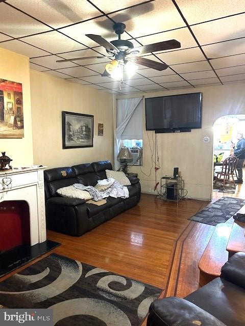 living room featuring ceiling fan, cooling unit, a drop ceiling, and hardwood / wood-style floors