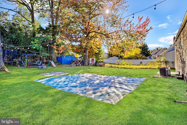 view of yard with a trampoline, a playground, basketball hoop, cooling unit, and a storage shed