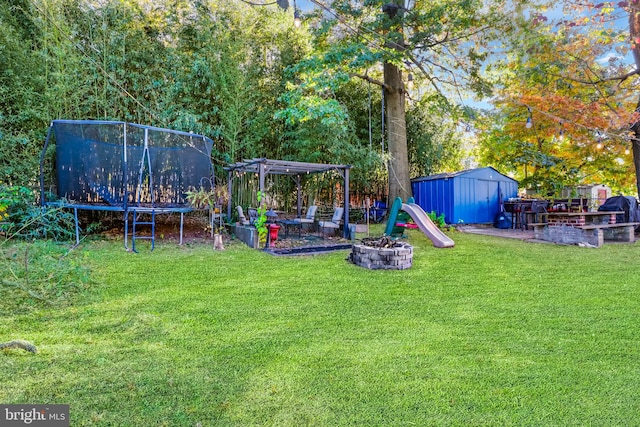 view of yard featuring an outdoor fire pit, a shed, and a trampoline