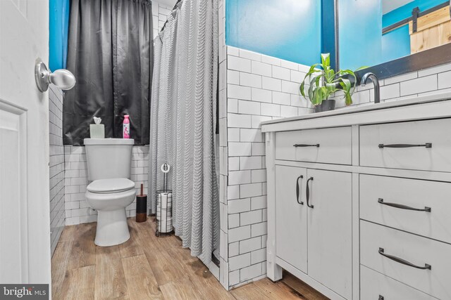 bathroom with hardwood / wood-style floors, toilet, tile walls, and a shower with shower curtain