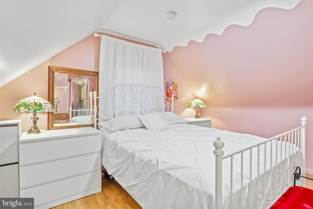 bedroom with vaulted ceiling and light hardwood / wood-style floors