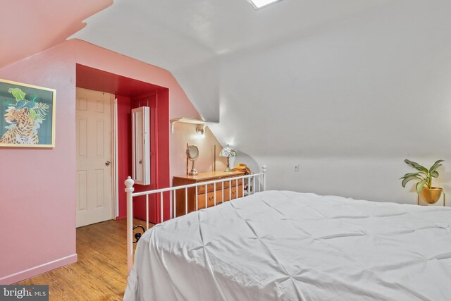 bedroom with vaulted ceiling and light hardwood / wood-style floors