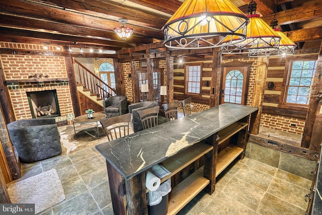 dining area with a notable chandelier, beamed ceiling, wood ceiling, and a brick fireplace