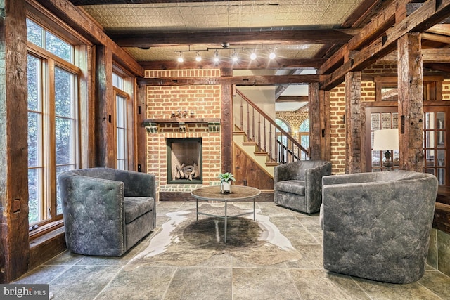 living room with beamed ceiling, a fireplace, and rail lighting