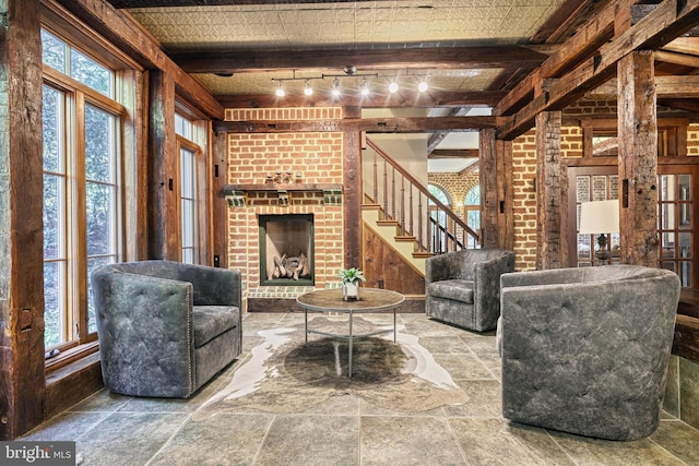 995 Black Gap Rd, Fayetteville, PA 17222 - living room featuring stone tile flooring, brick wall, a brick fireplace, track lighting, and stairs