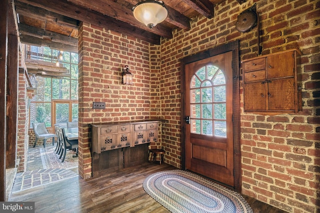 foyer entrance with brick wall, beamed ceiling, and hardwood / wood-style floors