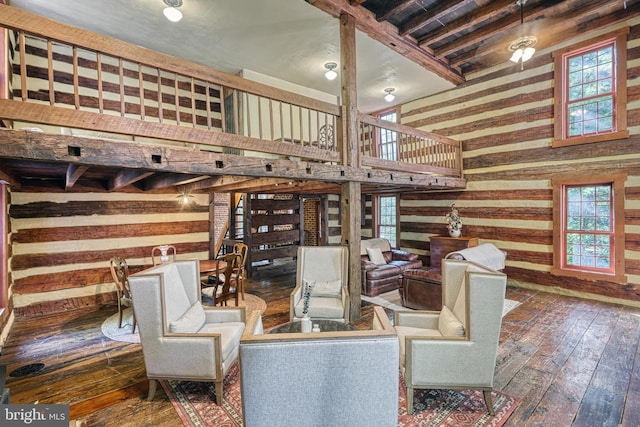 interior space featuring a towering ceiling, beamed ceiling, plenty of natural light, and dark hardwood / wood-style flooring