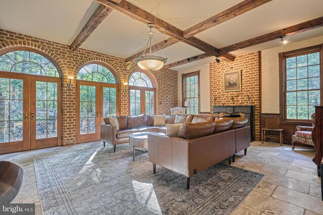 995 Black Gap Rd, Fayetteville, PA 17222 - living area with beam ceiling, a brick fireplace, stone tile floors, a wainscoted wall, and french doors