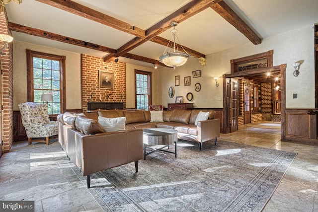 living room with beam ceiling, brick wall, and a brick fireplace