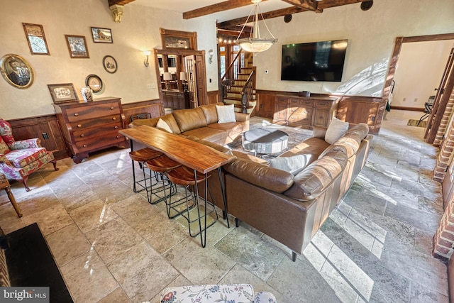 living room featuring beam ceiling and wood walls