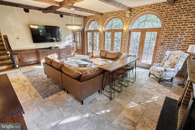 living room with french doors, beam ceiling, and brick wall