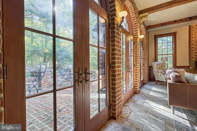 doorway to outside with french doors, brick wall, and beamed ceiling