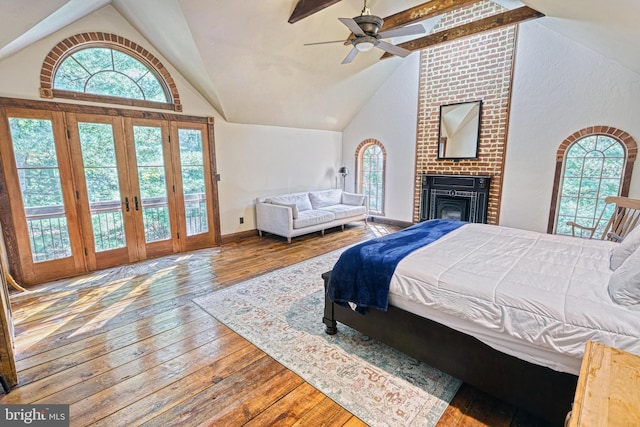 bedroom featuring a fireplace, wood-type flooring, high vaulted ceiling, and ceiling fan