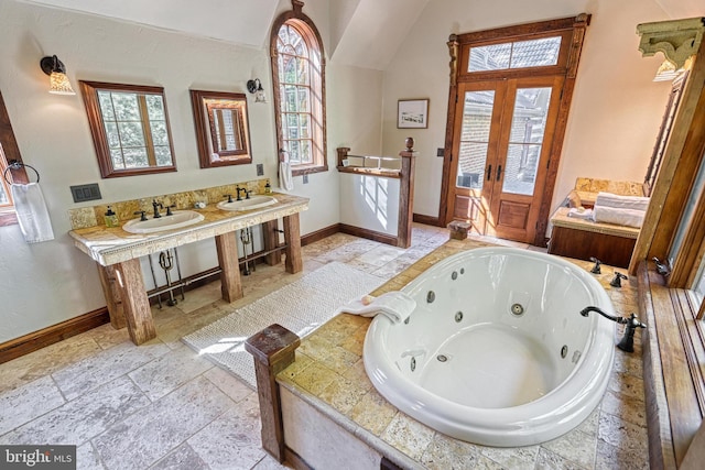 bathroom with french doors, sink, and tiled bath