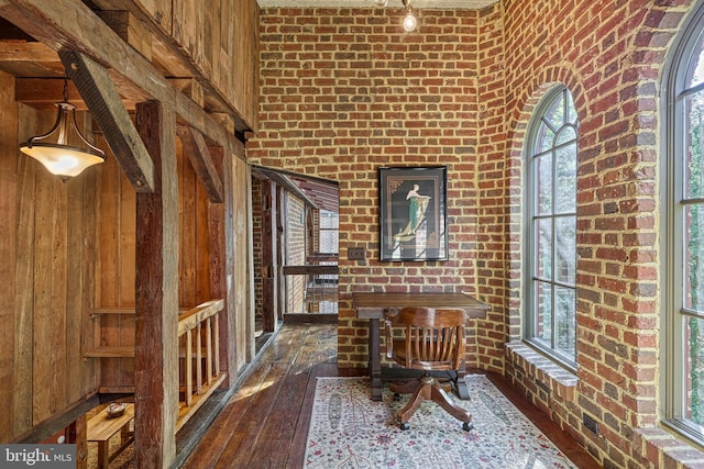 interior space with wood walls, brick wall, and dark hardwood / wood-style flooring