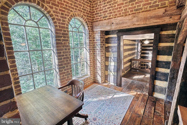 office area with a healthy amount of sunlight, hardwood / wood-style flooring, and brick wall