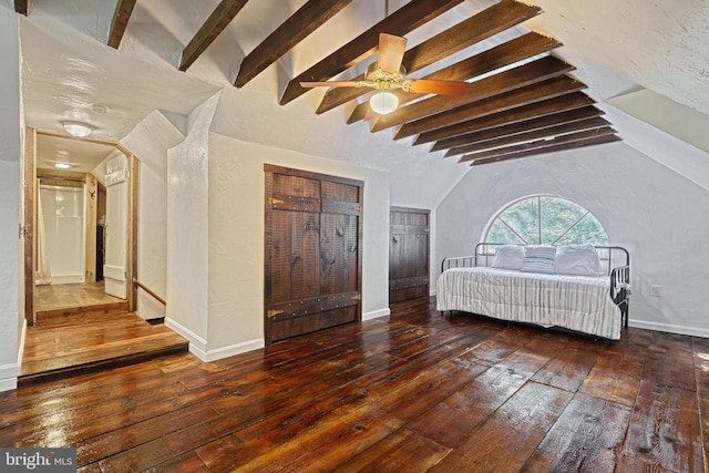 unfurnished bedroom featuring dark hardwood / wood-style floors, lofted ceiling with beams, and ceiling fan