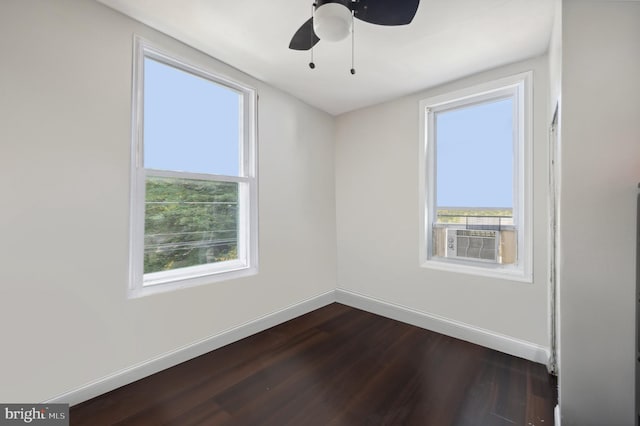 empty room featuring dark wood-type flooring, cooling unit, ceiling fan, and plenty of natural light