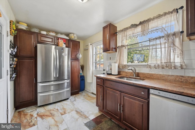 kitchen with white dishwasher, stainless steel fridge, and sink