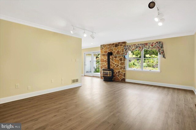 unfurnished living room with a wealth of natural light, track lighting, a wood stove, and dark hardwood / wood-style flooring