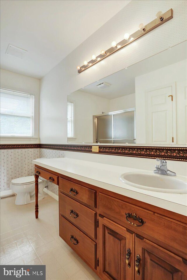 bathroom with vanity, tile patterned floors, toilet, and an enclosed shower