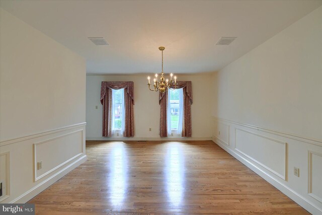 spare room featuring a notable chandelier and light hardwood / wood-style floors