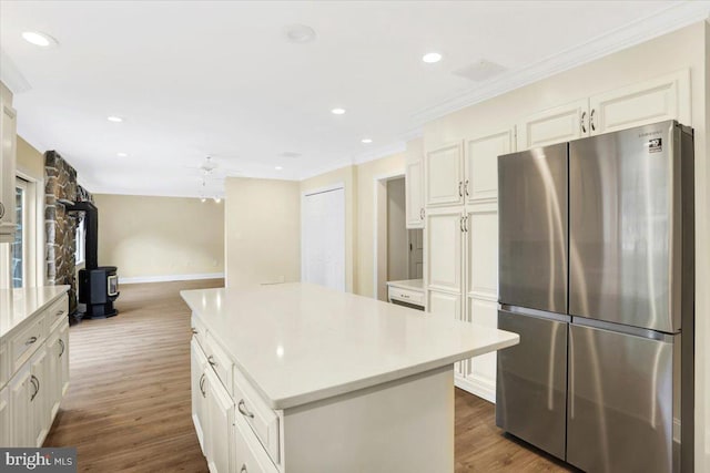 kitchen featuring stainless steel fridge, white cabinets, dark wood-type flooring, a wood stove, and a center island