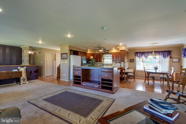 living room with light colored carpet, crown molding, sink, and ceiling fan with notable chandelier