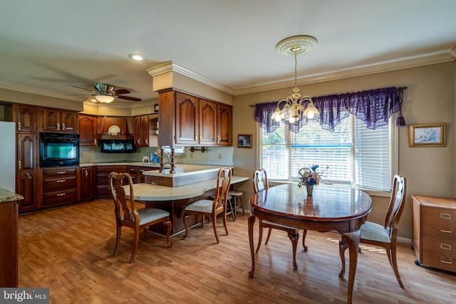 dining room with light hardwood / wood-style floors, crown molding, and ceiling fan with notable chandelier