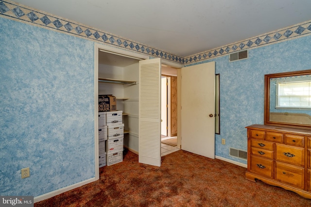 unfurnished bedroom with dark carpet and a closet