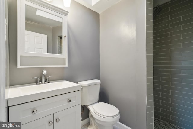 bathroom with vanity, toilet, and a tile shower