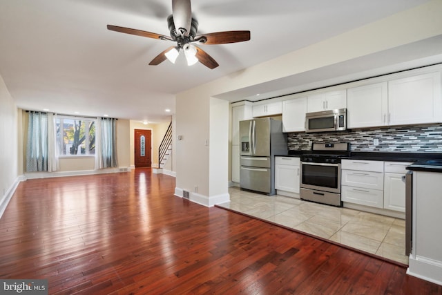 kitchen with backsplash, ceiling fan, stainless steel appliances, white cabinets, and light hardwood / wood-style flooring