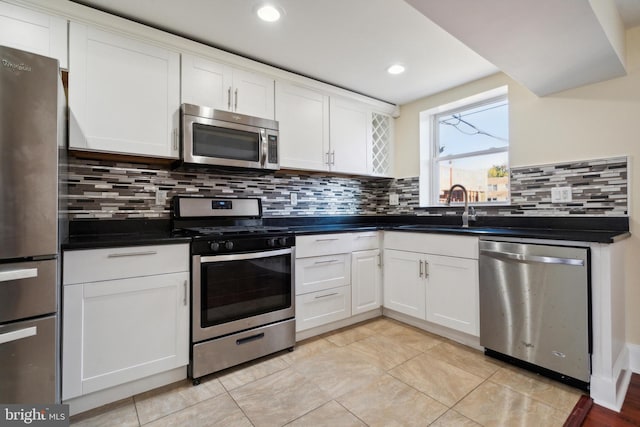 kitchen featuring decorative backsplash, white cabinetry, stainless steel appliances, and sink