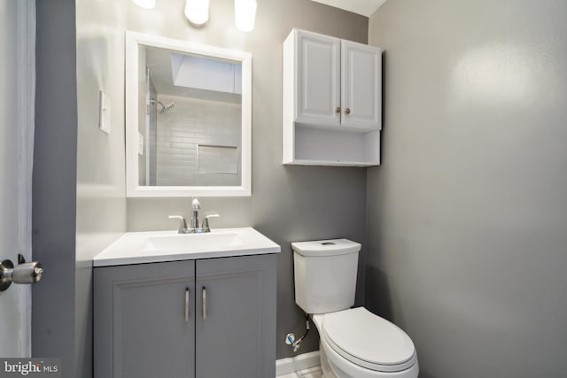 bathroom with vanity, tiled shower, and toilet