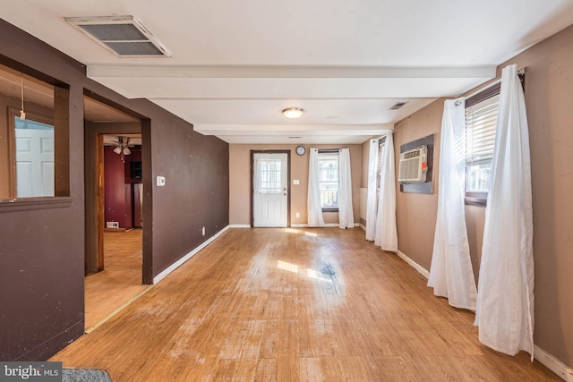 foyer entrance with light hardwood / wood-style floors, a wall mounted AC, beam ceiling, and ceiling fan