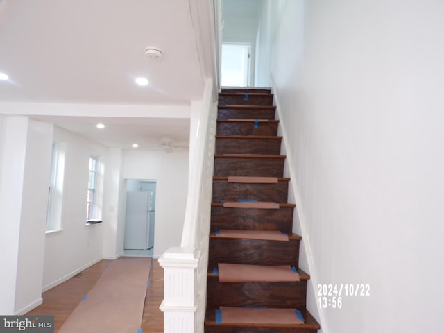 stairway with ceiling fan, hardwood / wood-style flooring, and plenty of natural light