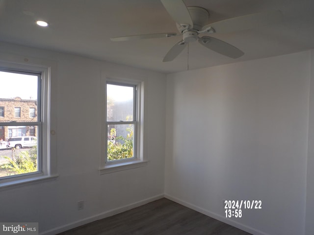 spare room featuring dark wood-type flooring, ceiling fan, and a healthy amount of sunlight