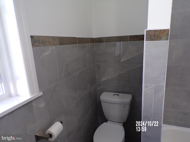 bathroom featuring toilet and tile walls