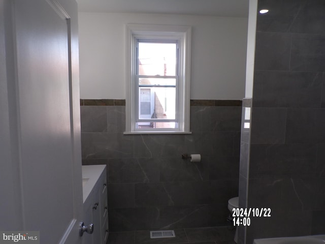 bathroom featuring toilet, vanity, tile walls, and tile patterned flooring