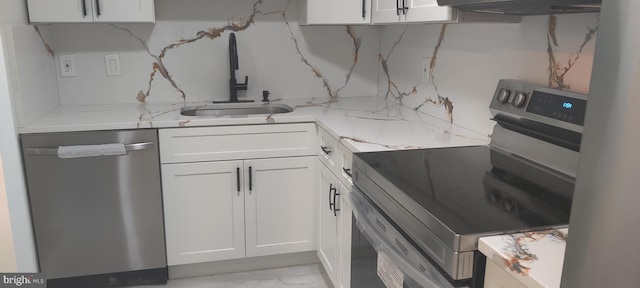 kitchen with light stone countertops, white cabinetry, sink, and stainless steel appliances