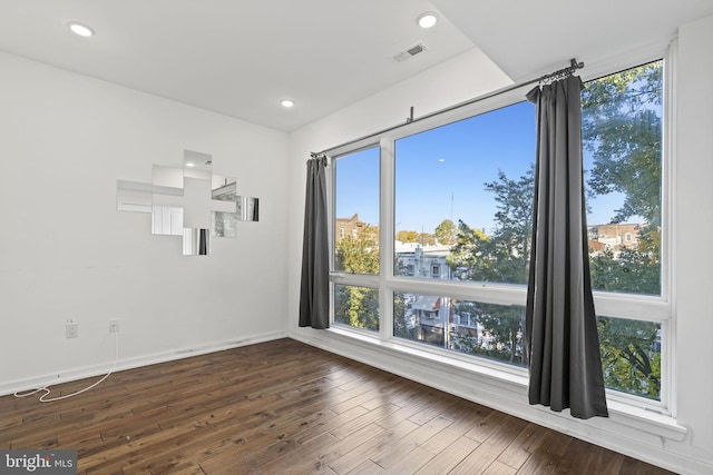 empty room with dark wood-style flooring, visible vents, recessed lighting, and baseboards