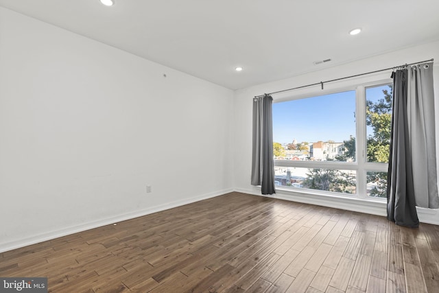 unfurnished room featuring recessed lighting, baseboards, a wealth of natural light, and dark wood-type flooring