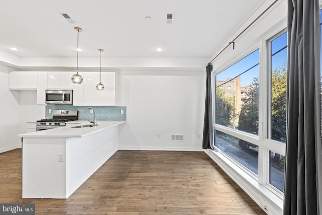 kitchen with decorative backsplash, white cabinets, visible vents, stainless steel appliances, and dark wood-style floors