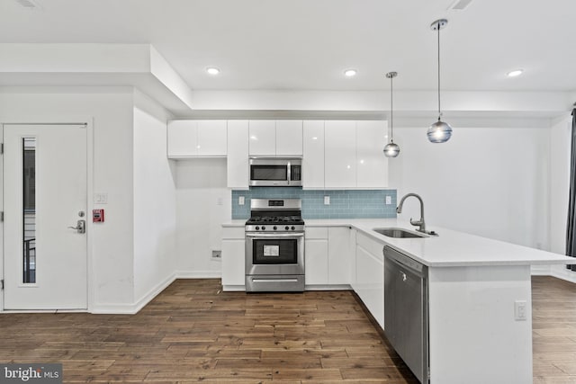 kitchen with dark hardwood / wood-style floors, stainless steel appliances, sink, pendant lighting, and white cabinetry