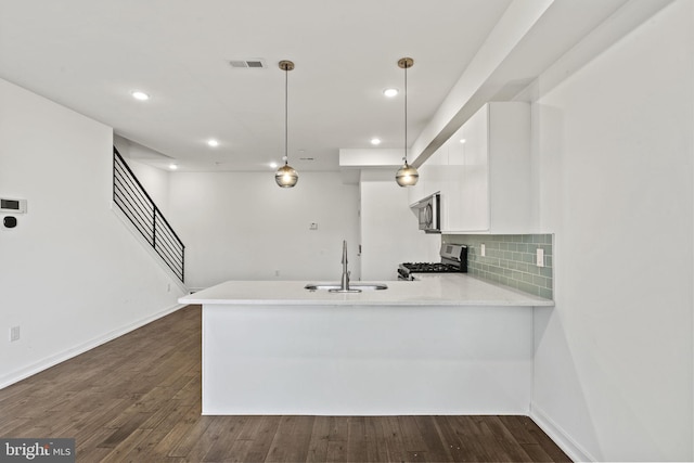 kitchen featuring kitchen peninsula, decorative light fixtures, stainless steel appliances, and sink